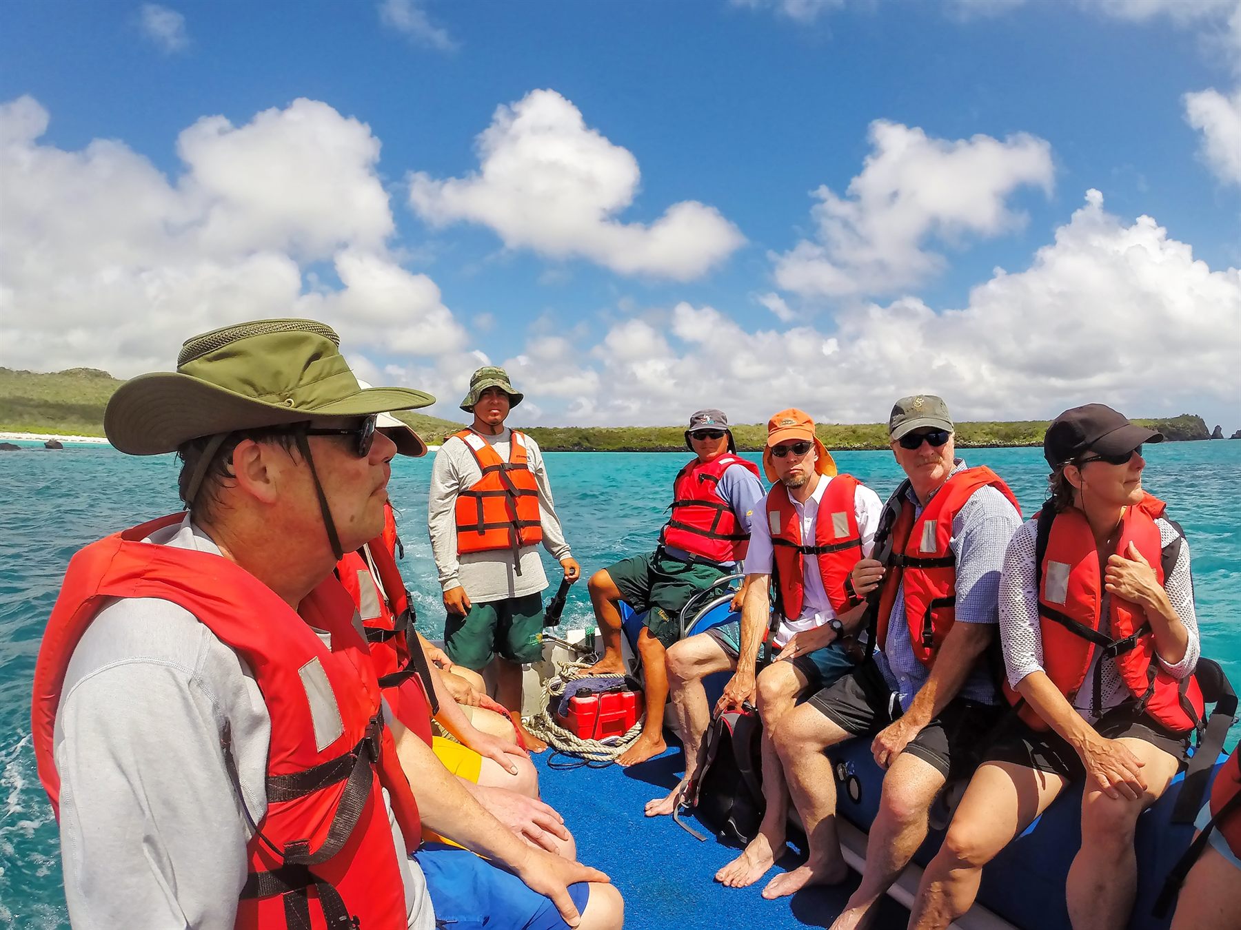 Travelers in life jackets riding in a panga dinghy on turquoise water